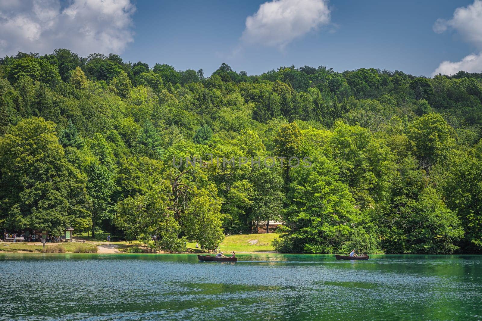 Tourists paddling in two paddleboats on emerald green lake in Plitvice Lakes National Park UNESCO World Heritage in Croatia