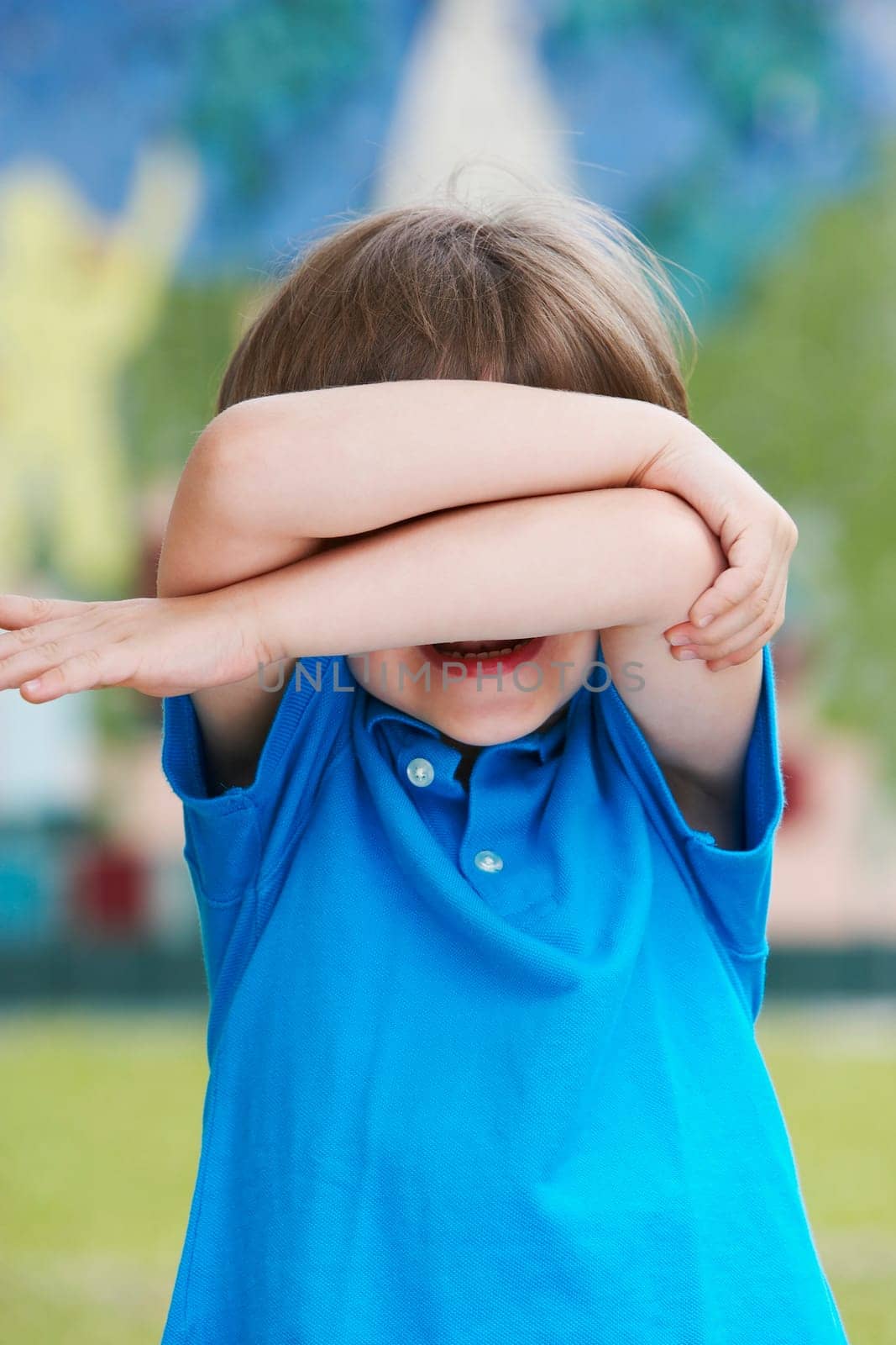 Close-up of a boy hiding his face with his arms and crying