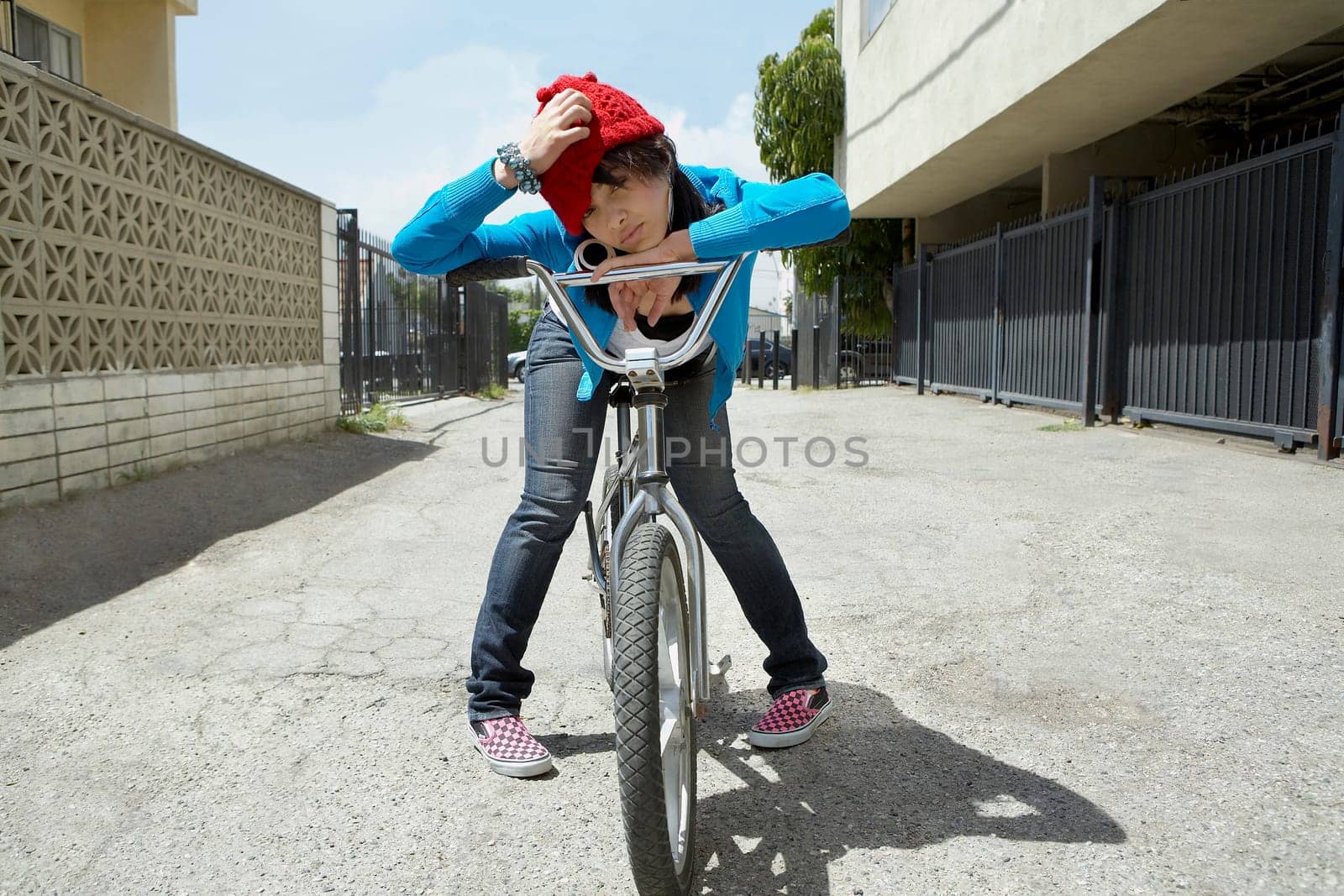 Young woman sitting on a bicycle and scratching her head
