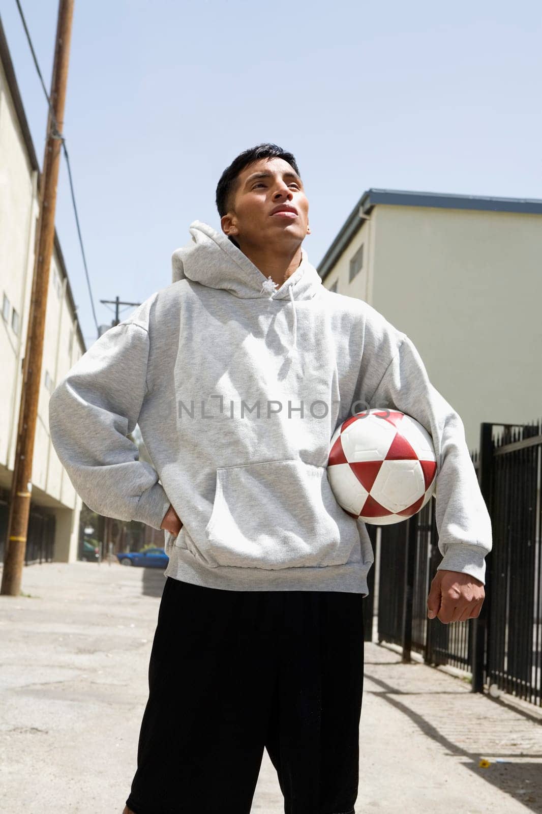 Young man standing on the street holding a soccer ball