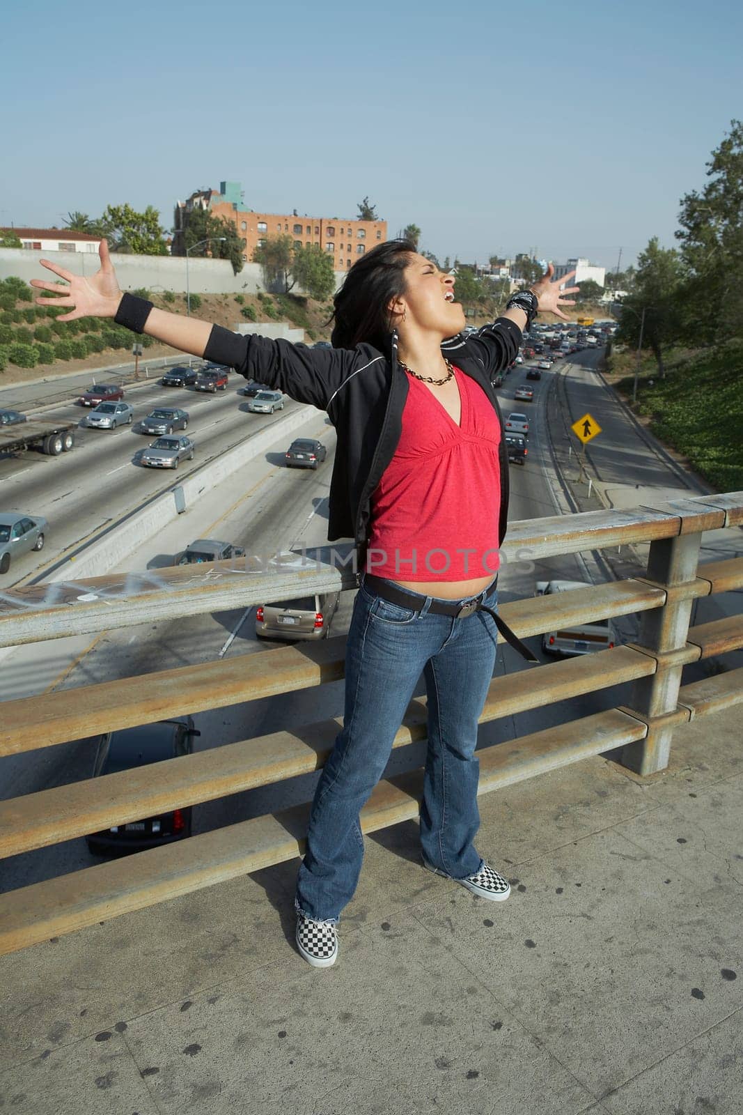 Young woman standing on an overpass with her arms outstretched