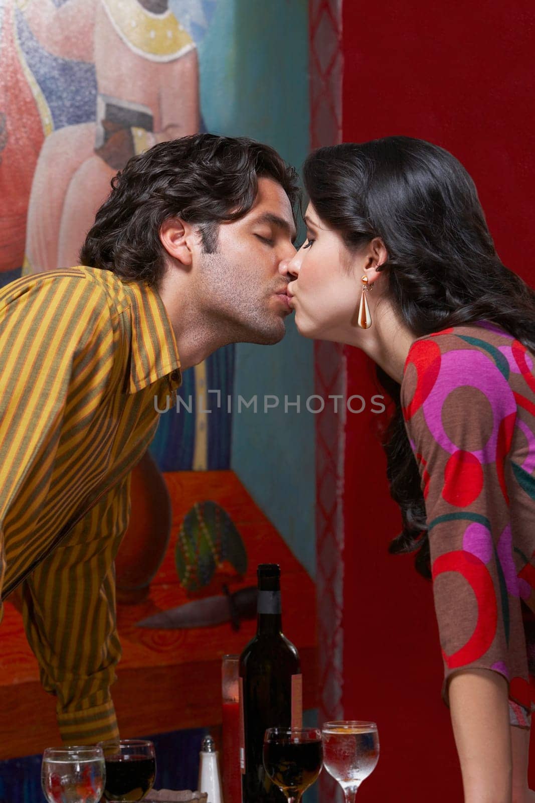 Side profile of a young couple kissing each other in a restaurant