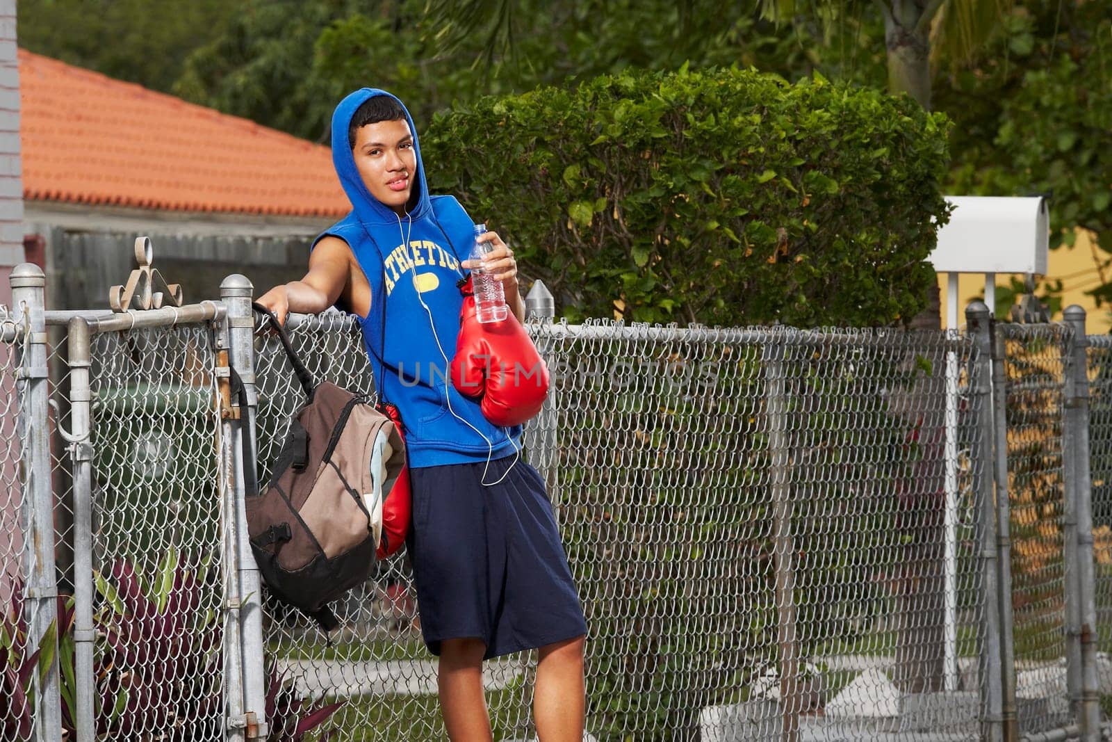 Side profile of a teenage boy listening an ipod and holding a bottle of water