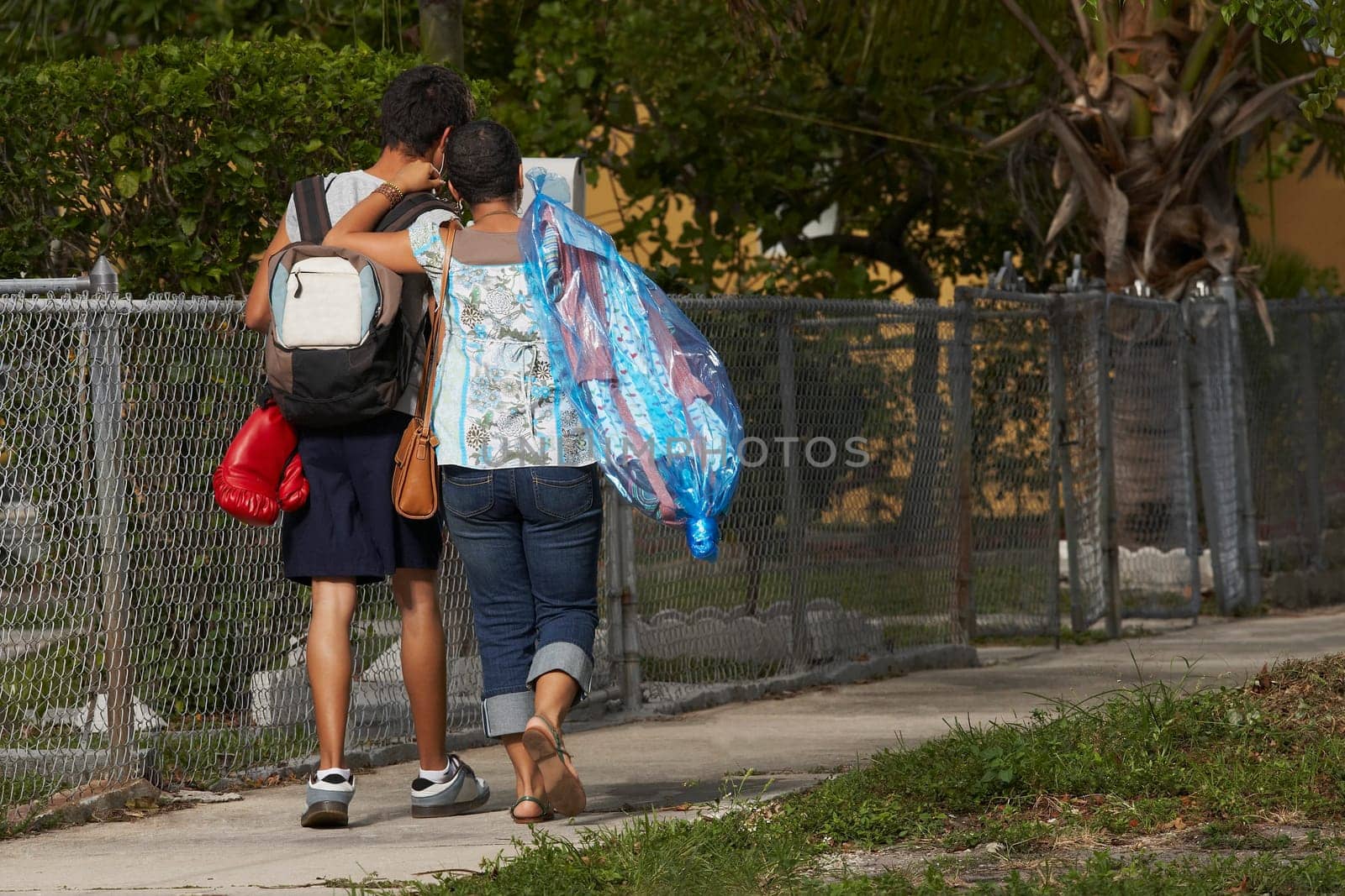 Rear view of a teenage boy and his sister walking on the walkway