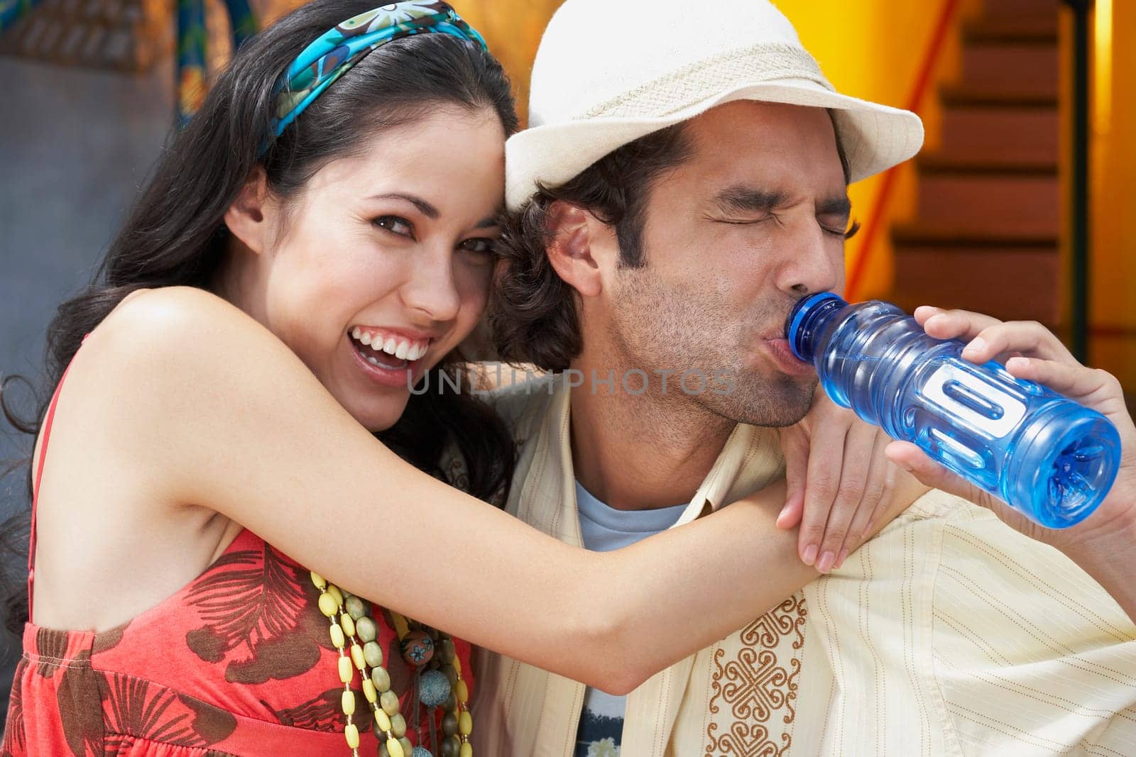Close-up of a young woman smiling with a young man drinking water from a water bottle