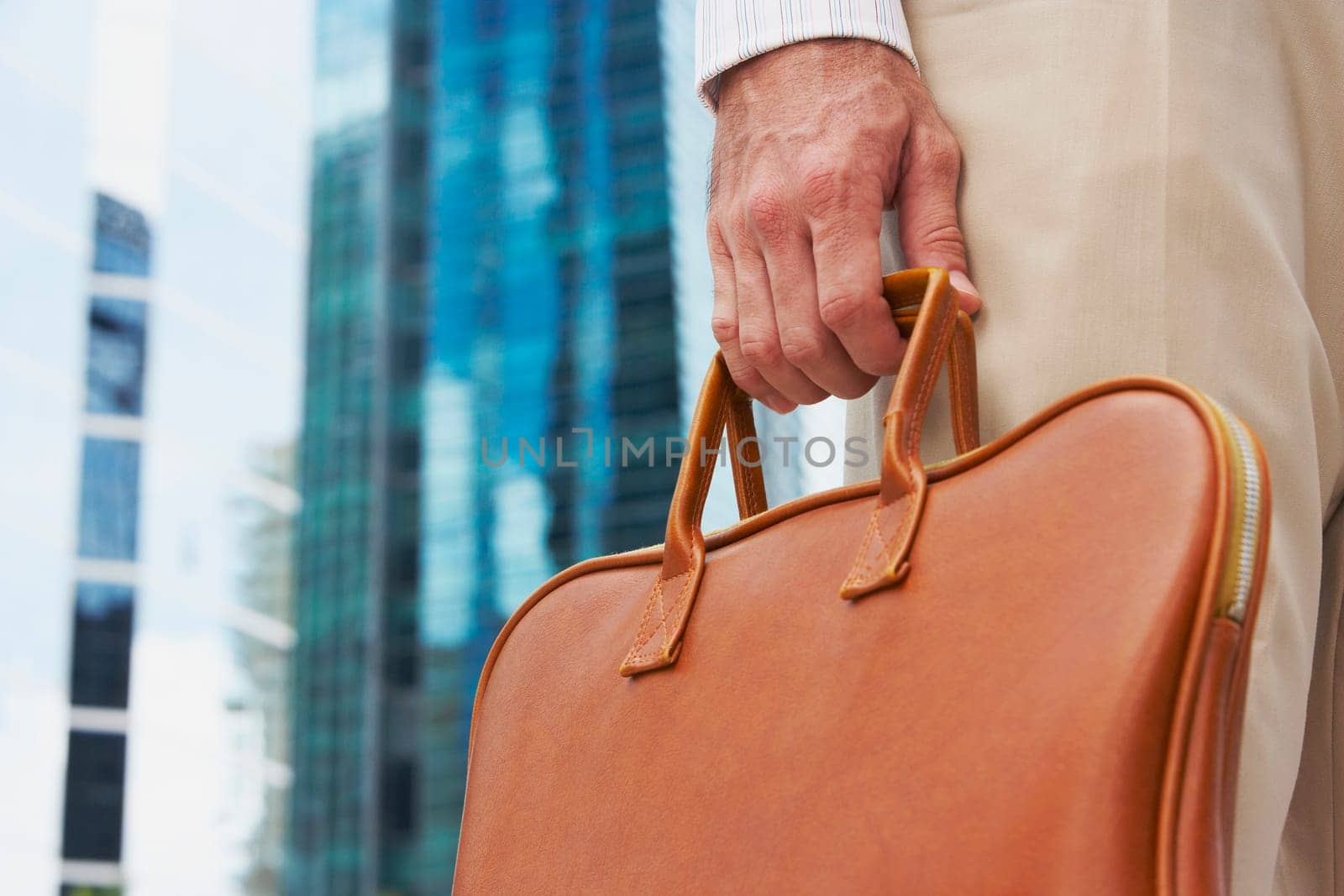 Mid section view of a businessman holding a handbag