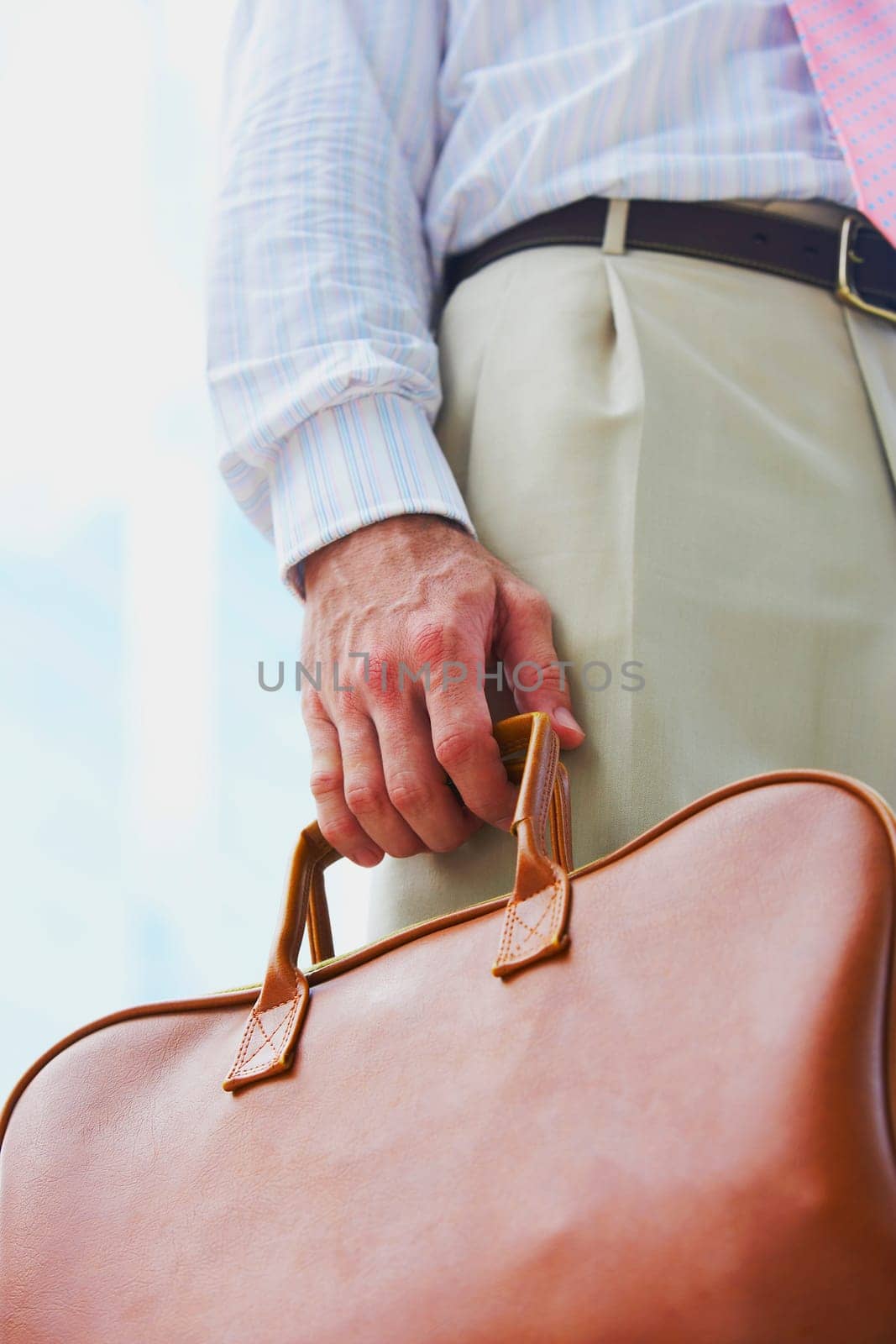 Mid section view of a businessman holding a handbag