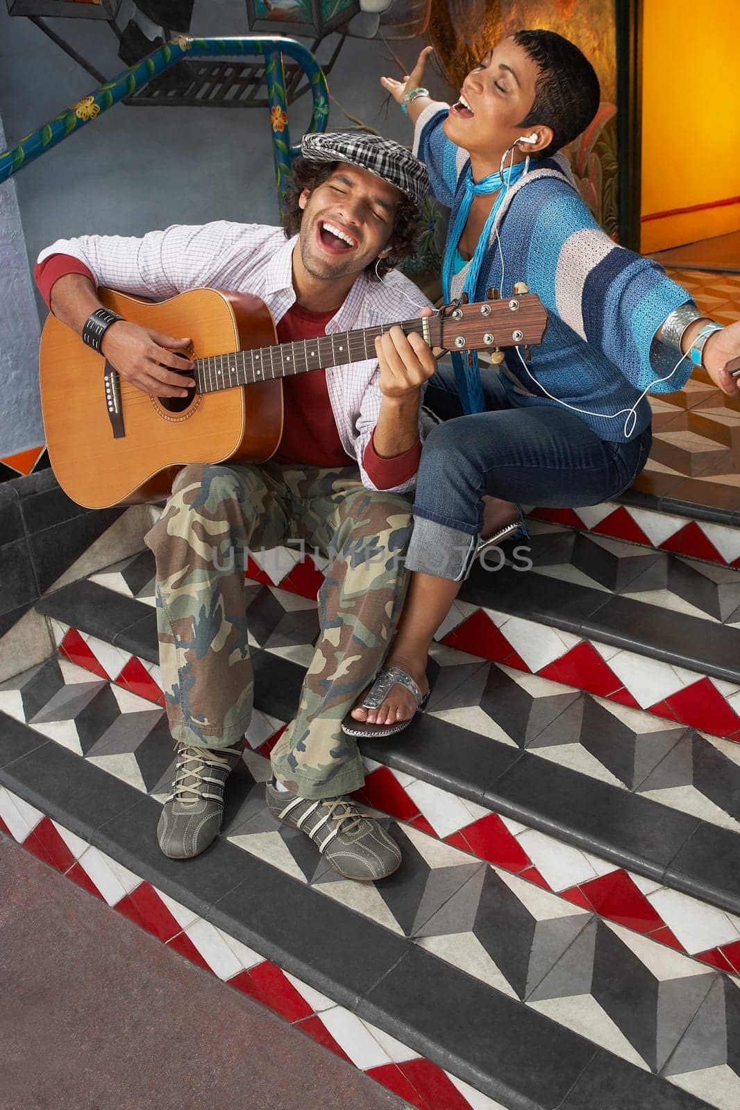 High angle view of a young man singing with a young woman and playing a guitar