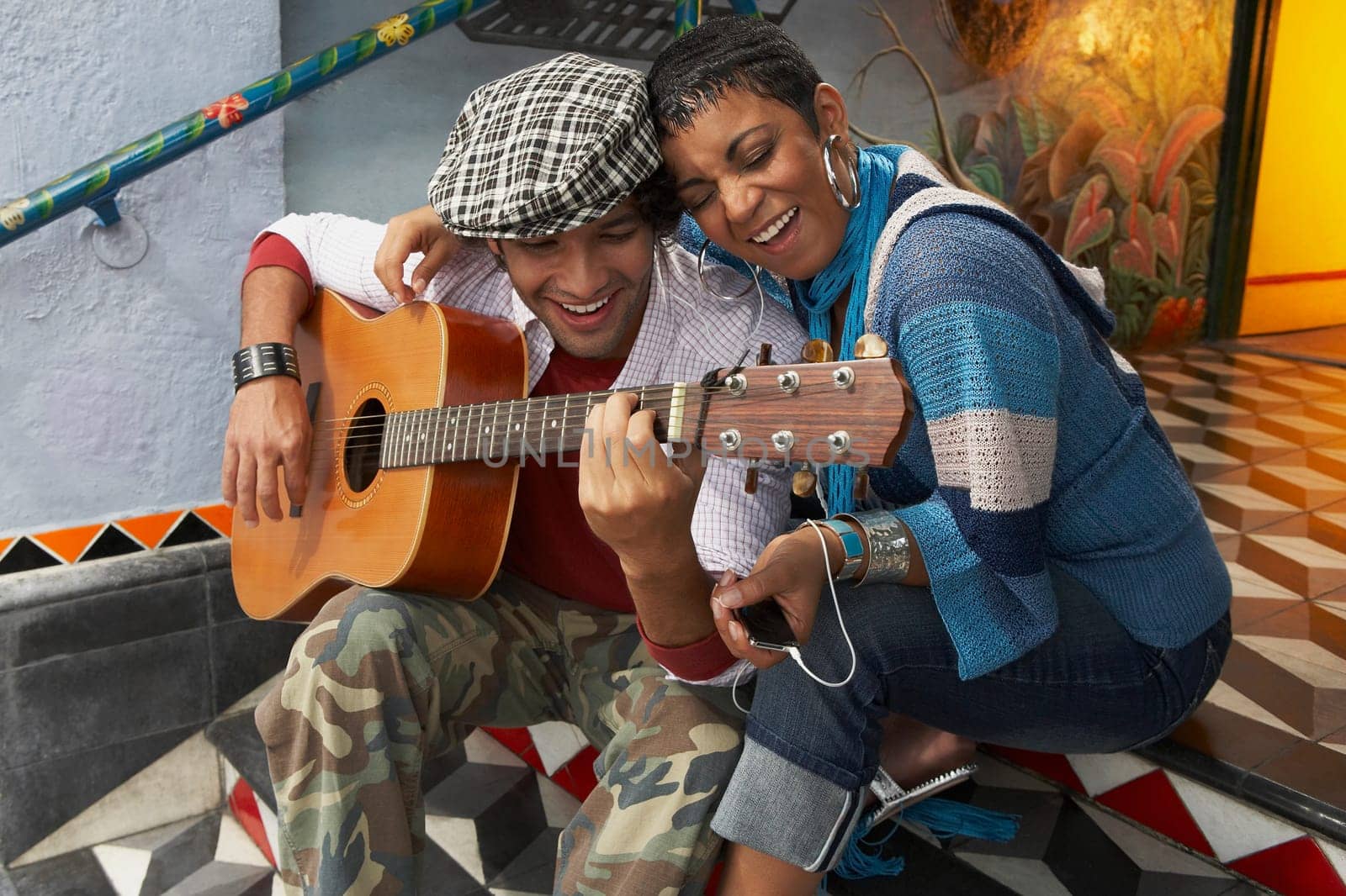 Young man playing a guitar and smiling with a young woman