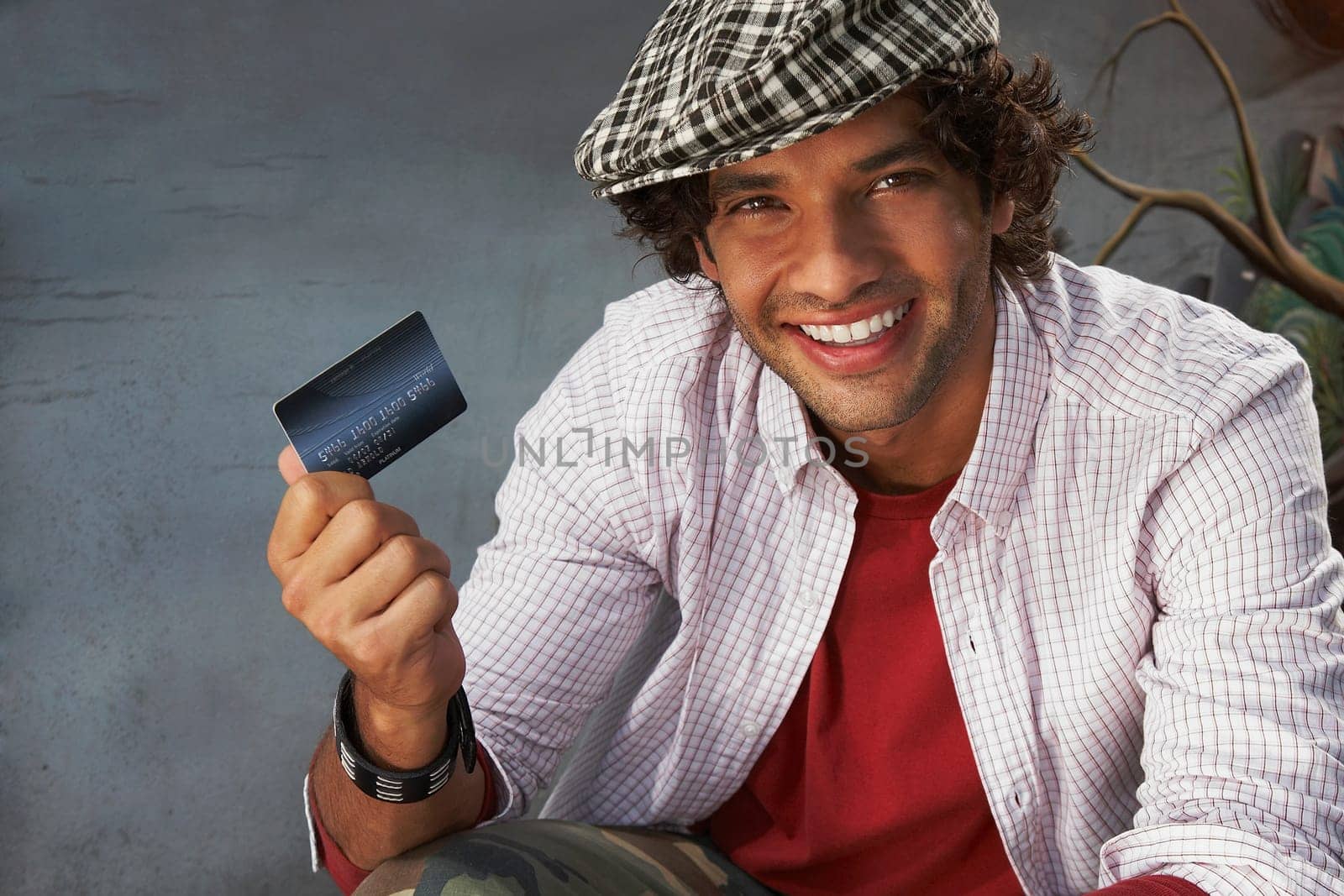 Portrait of a young man holding a credit card and smiling