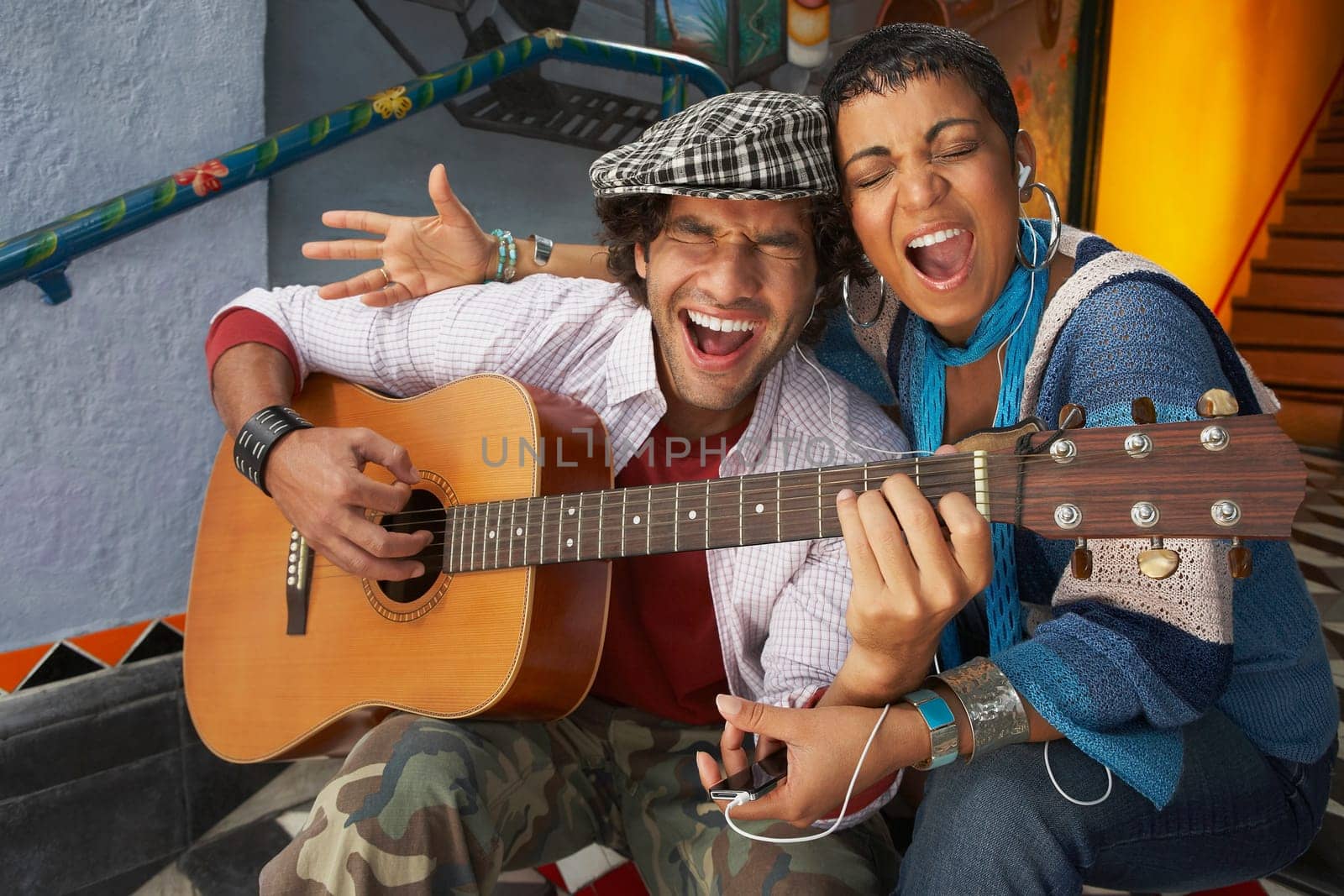 Close-up of a young man singing with a young woman and playing a guitar