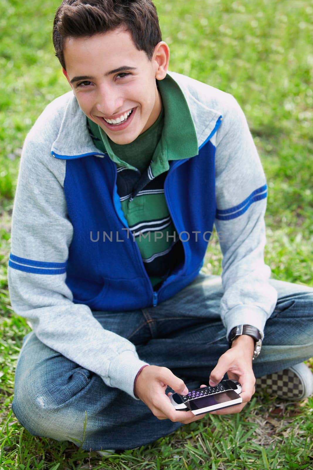 High angle view of a teenage boy smiling and using a mobile phone
