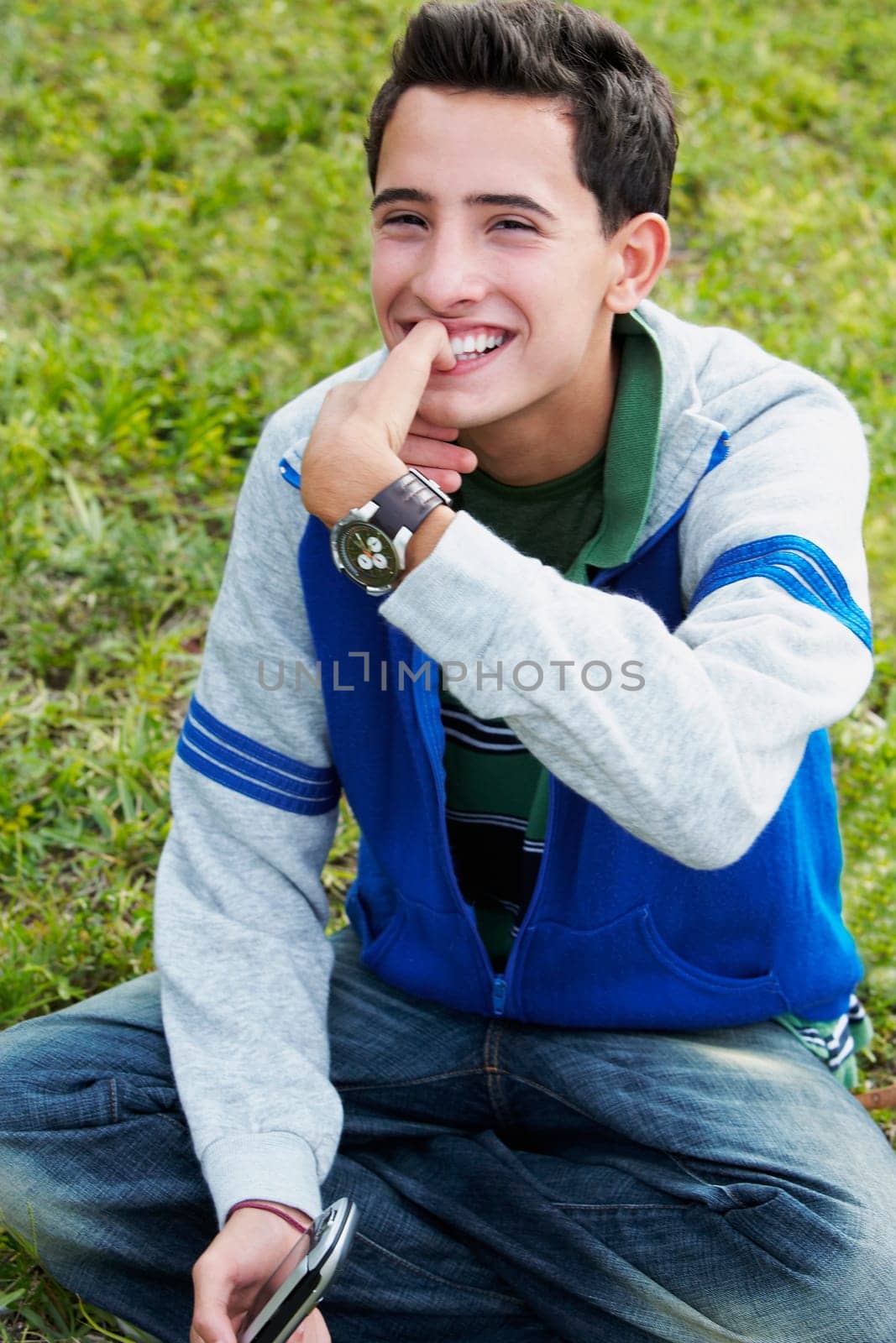 Close-up of a teenage boy smiling with his finger on his mouth