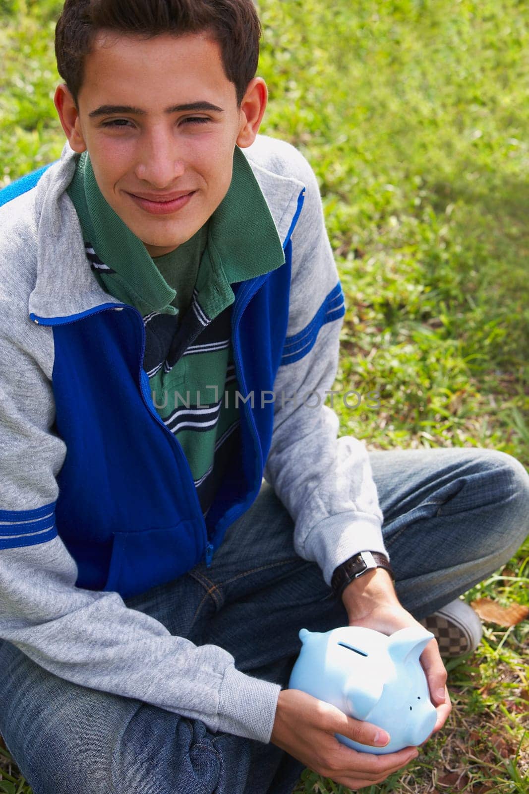 Close-up of a teenage boy holding a piggy bank