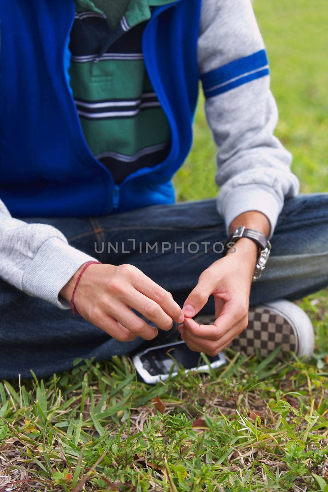 Low section view of a teenage boy sitting in a park