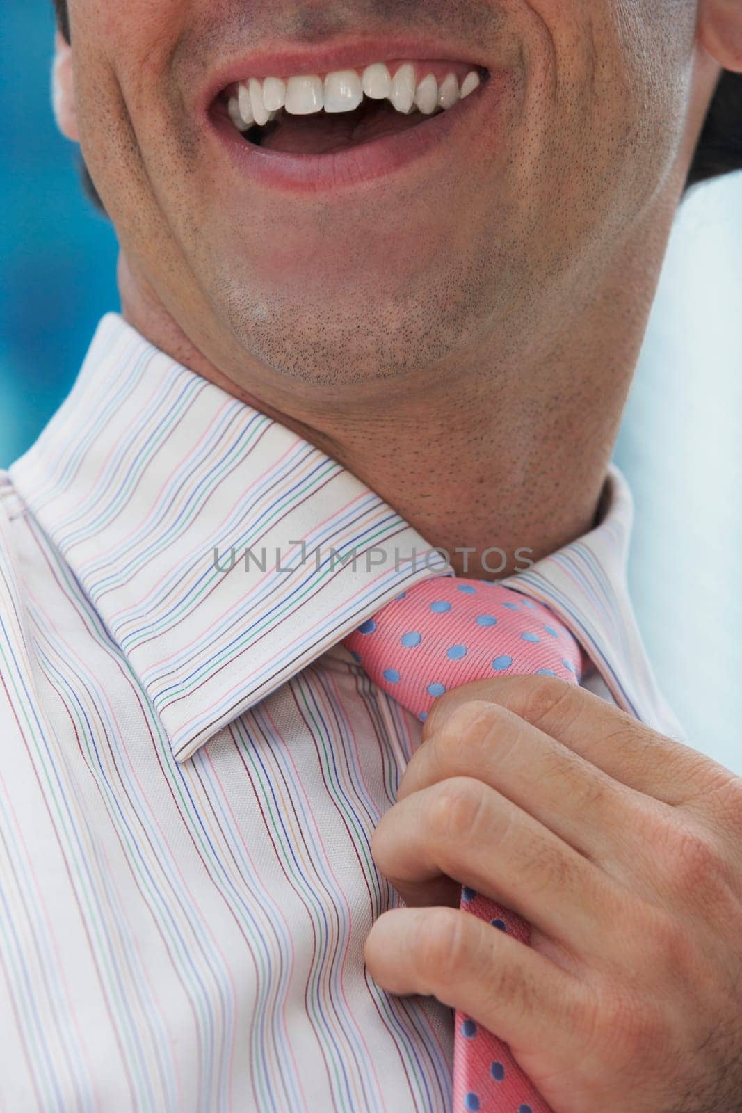 Close-up of a businessman adjusting his tie and smiling