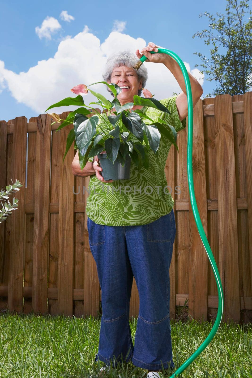 Portrait of a senior woman watering a potted plant
