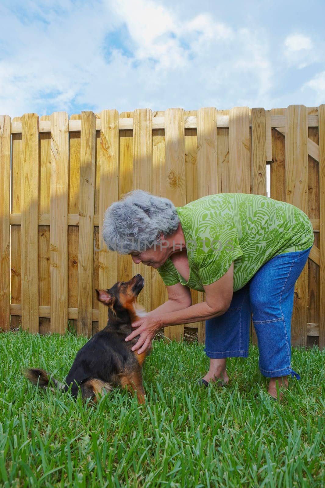 Side profile of a senior woman kissing a dog