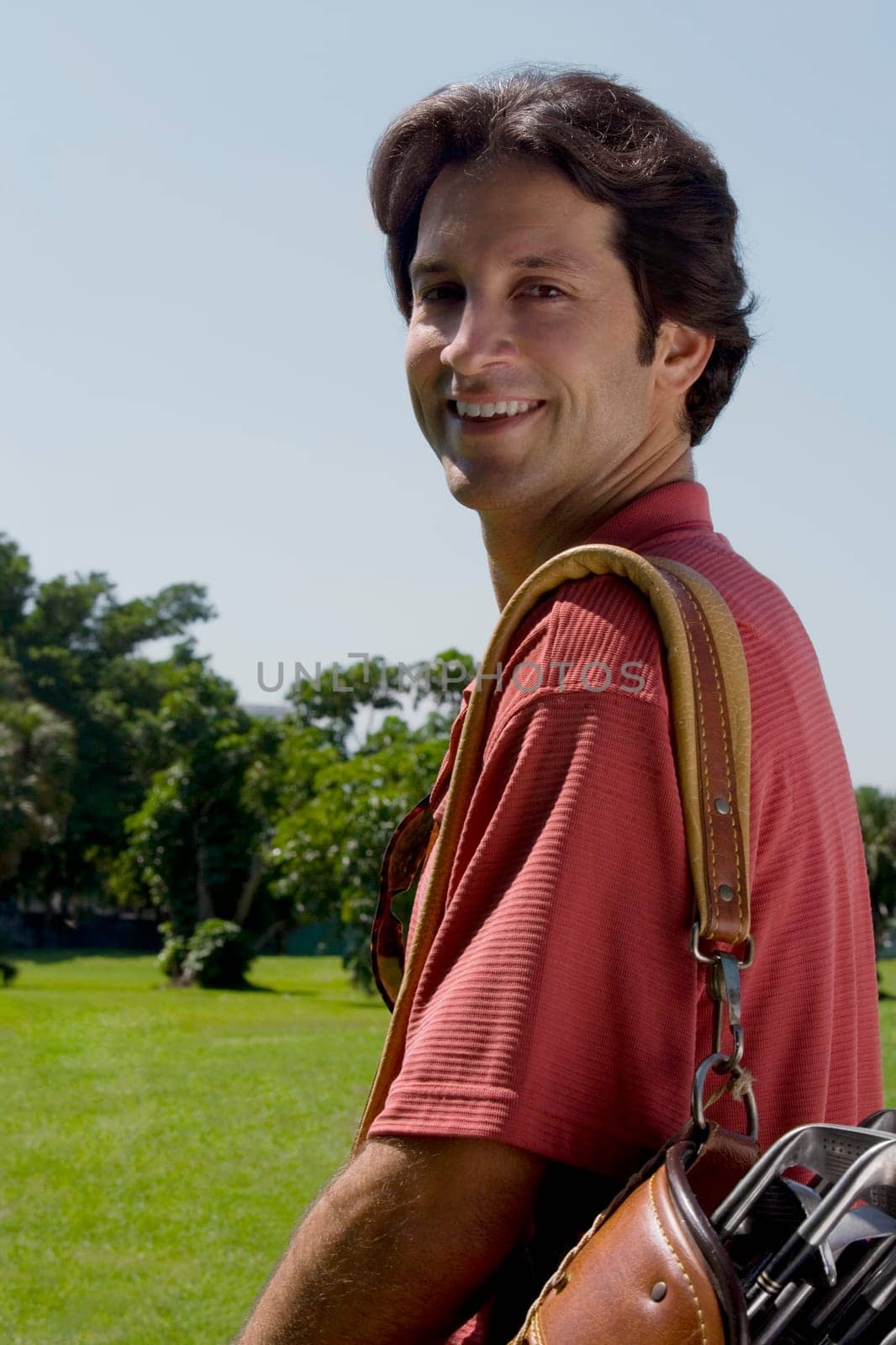 Portrait of a mid adult man carrying a golf bag and smiling