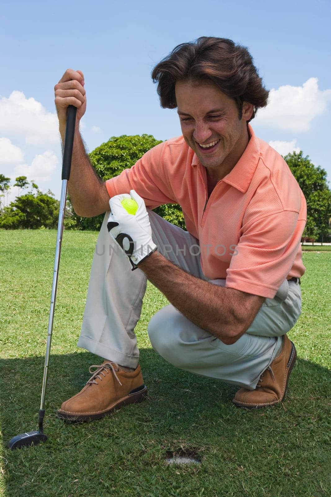 Mid adult man holding a golf ball and a golf club