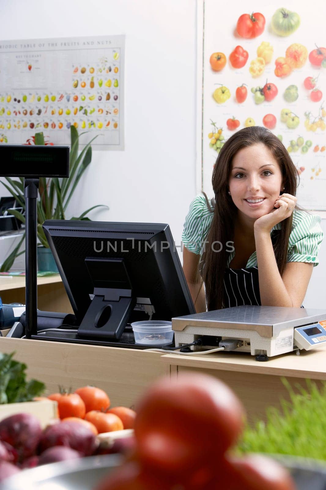 Portrait of a young woman leaning at a checkout counter and smiling