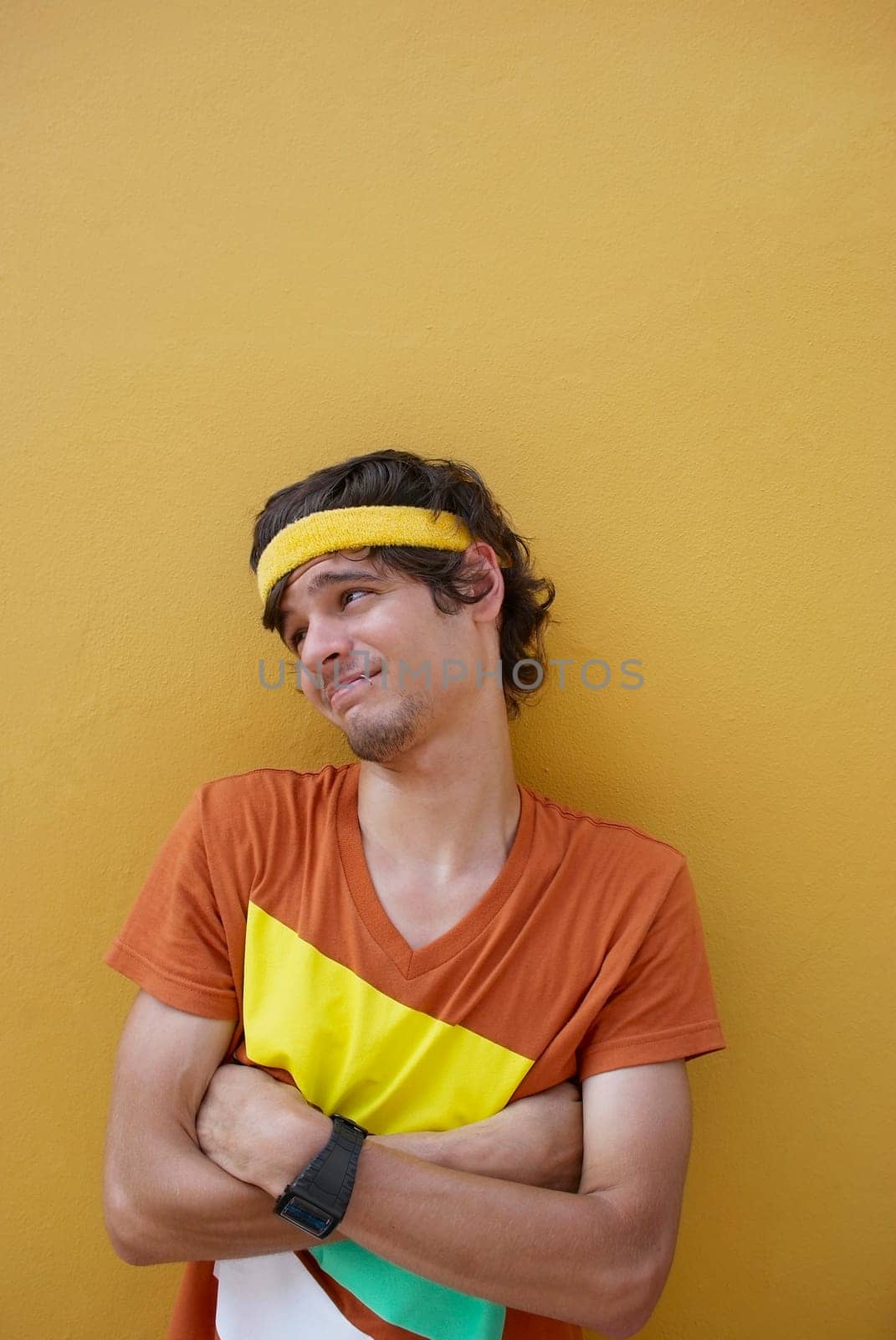 Young man standing with his arms crossed and making a face
