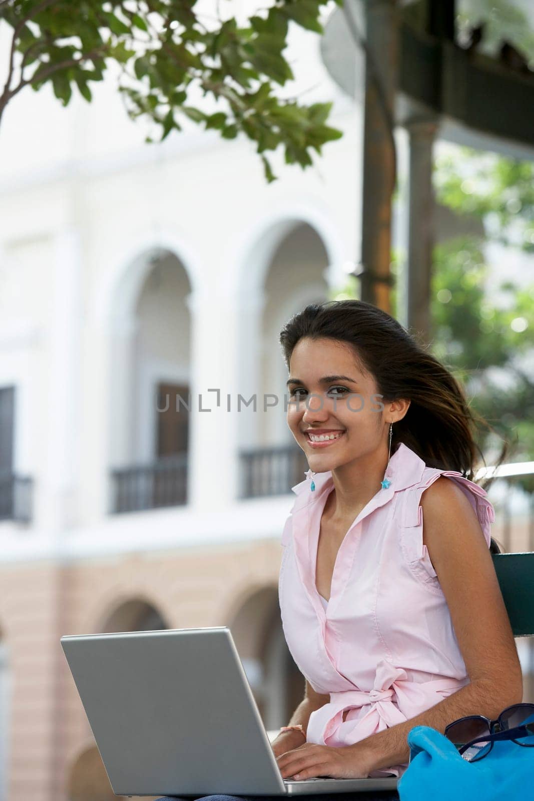 Portrait of a young woman using a laptop and smiling, Old San Juan, San Juan, Puerto Rico
