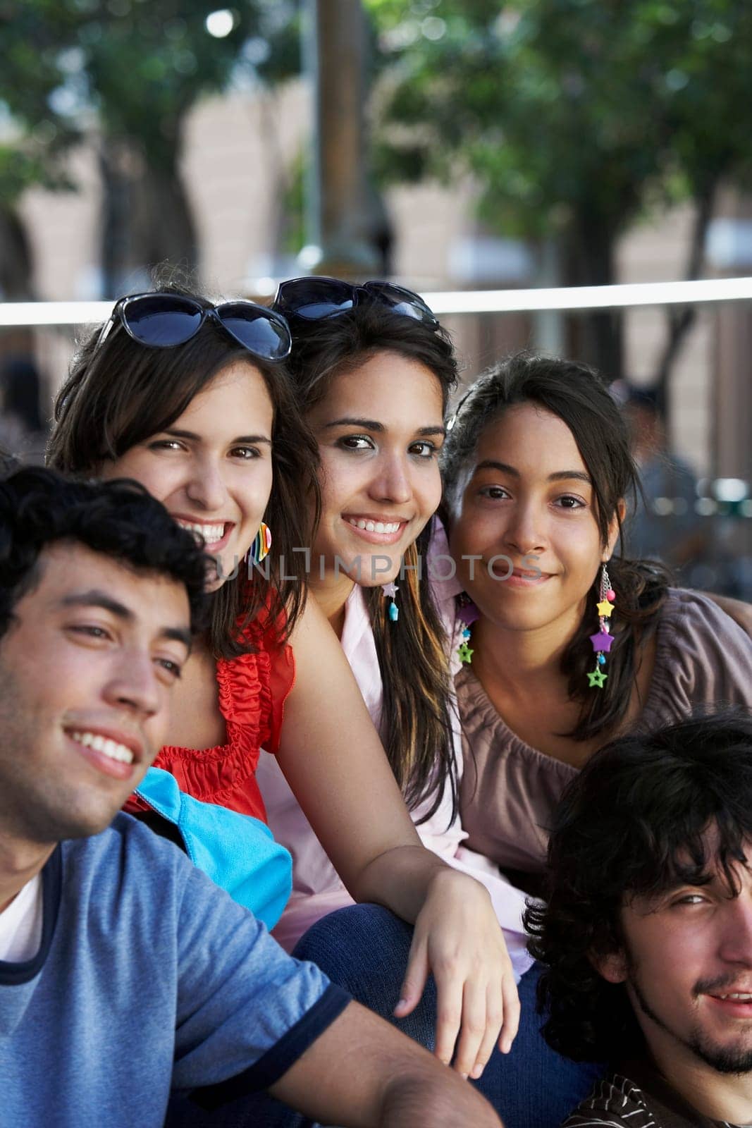 Portrait of three young women and two young men sitting together and smiling