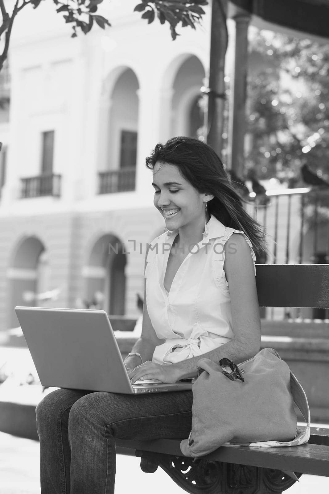 Close-up of a young woman sitting on a bench and using a laptop, Old San Juan, San Juan, Puerto Rico