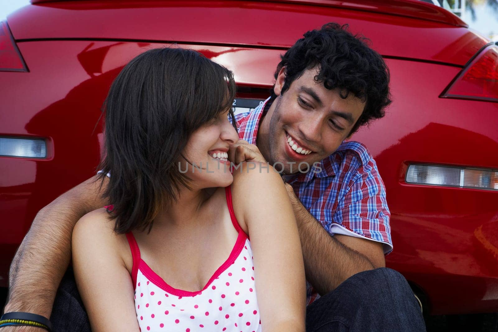Close-up of a young couple sitting in front of a car