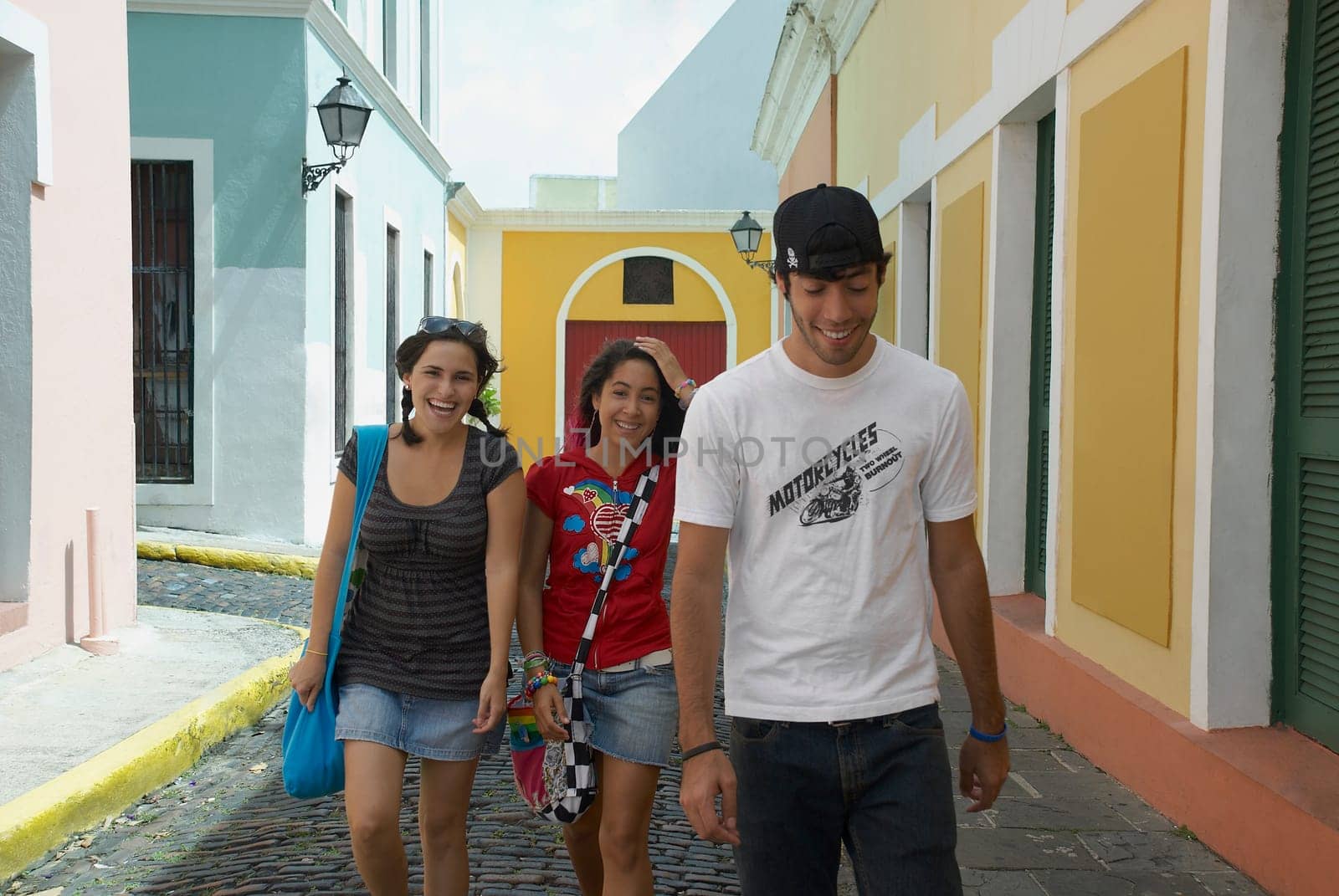 Young man walking with two young women on a cobblestone street, Old San Juan, San Juan, Puerto Rico