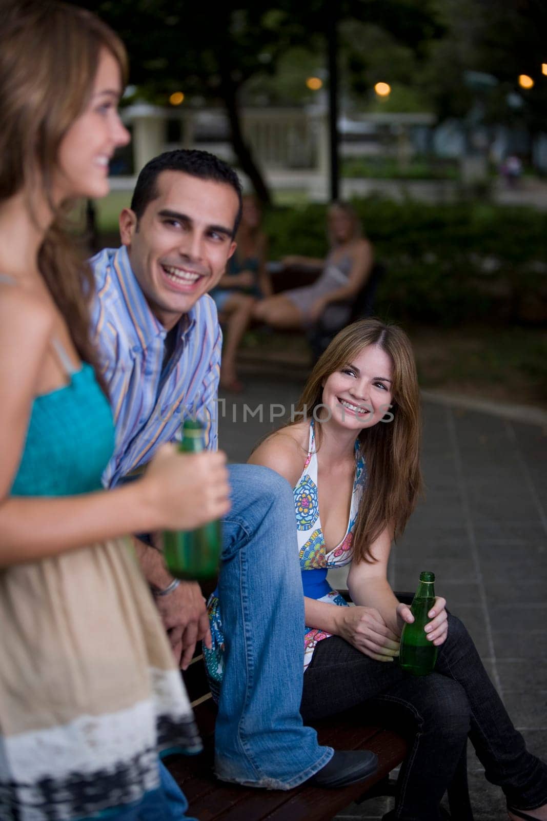 Young man sitting between two young women and smiling