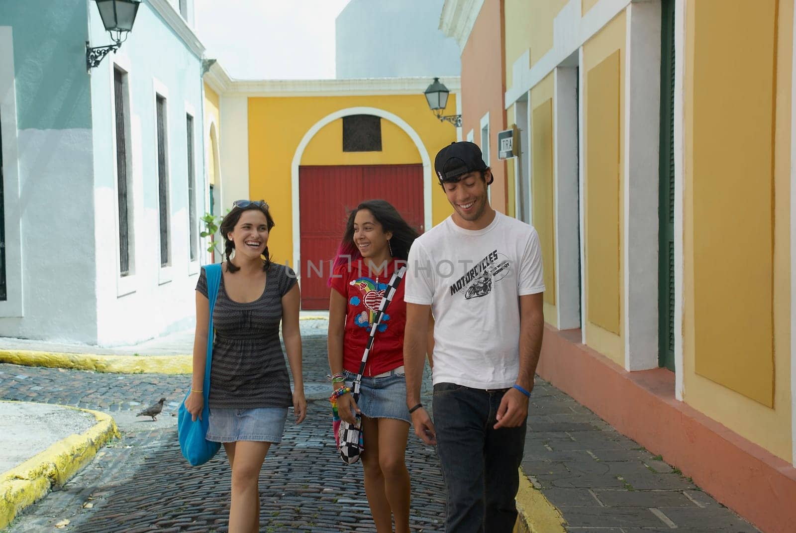 Young man walking with two young women on a cobblestone street, Old San Juan, San Juan, Puerto Rico