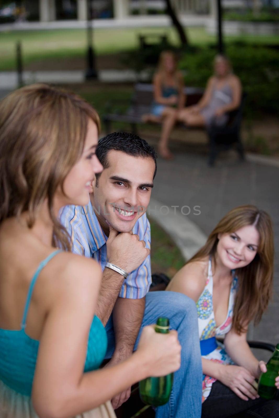 Portrait of a young man sitting between two young women and smiling