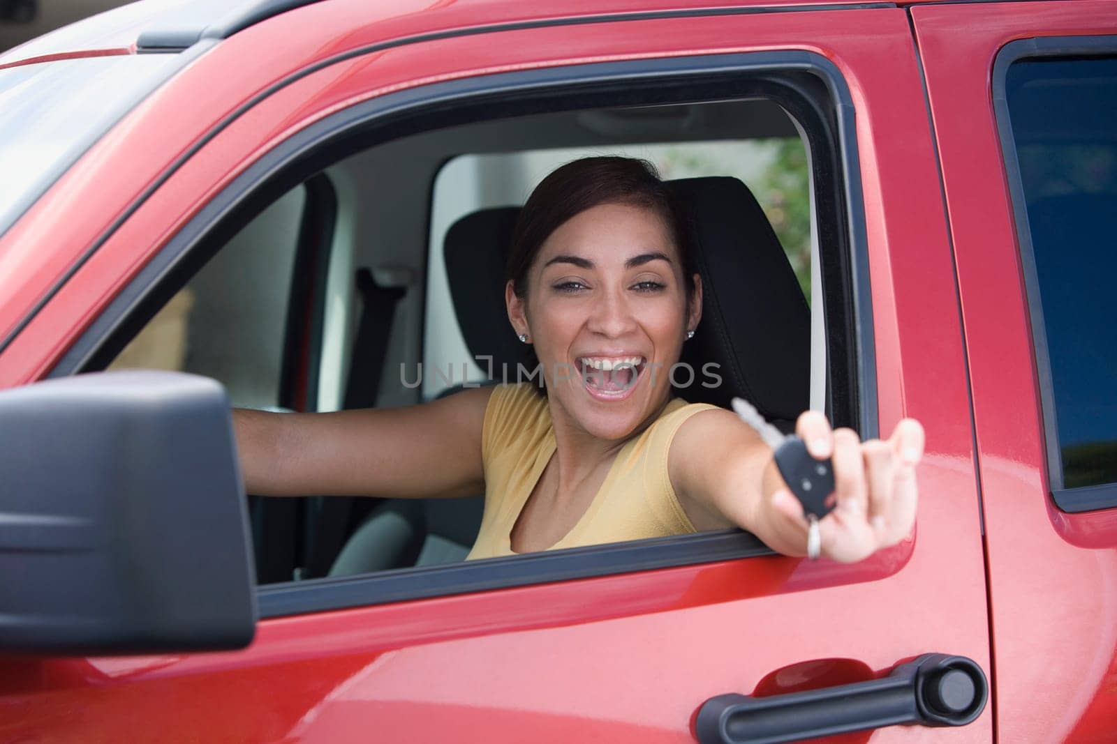 Portrait of a young woman sitting in a car and showing a car key