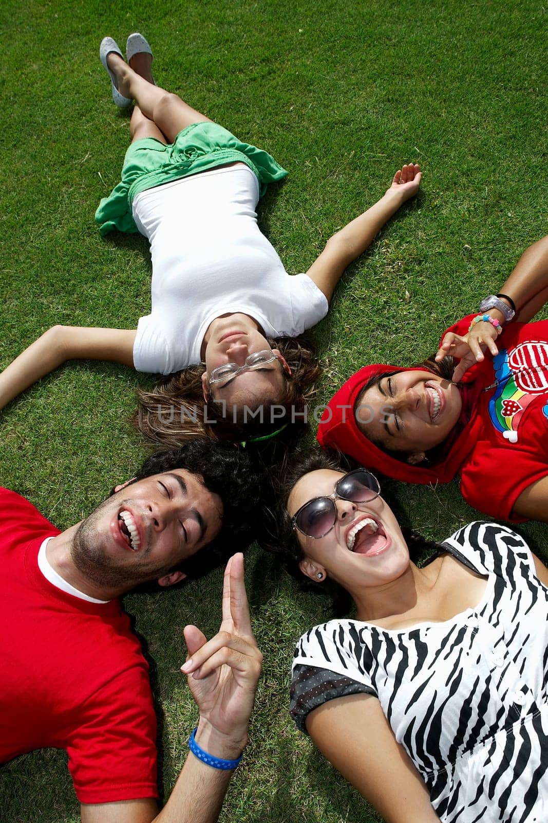 High angle view of a young man lying on grass with three young women
