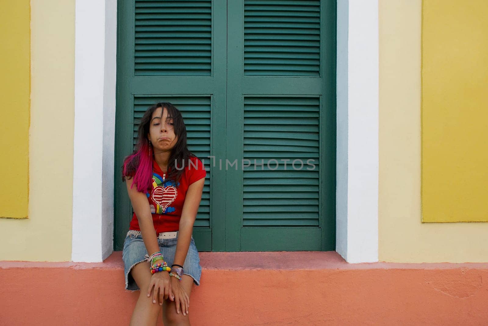 Young woman sitting on a window sill and making a face
