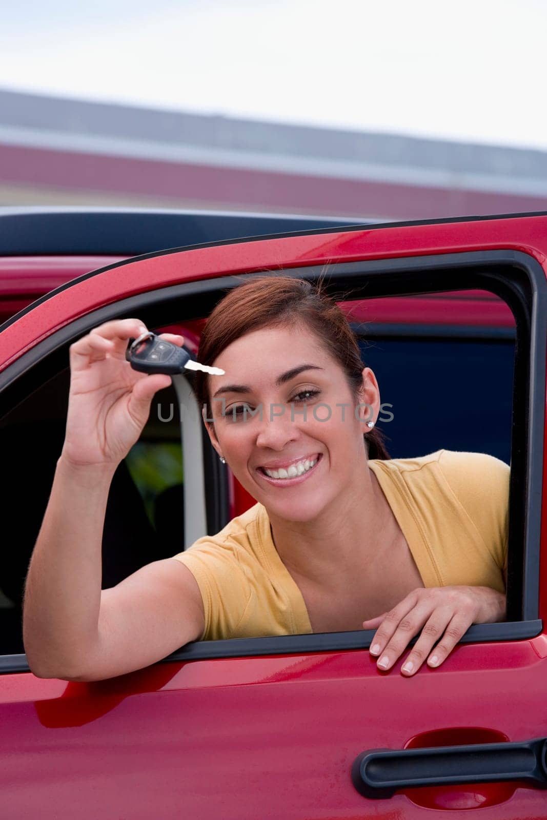 Portrait of a young woman showing a car key and smiling