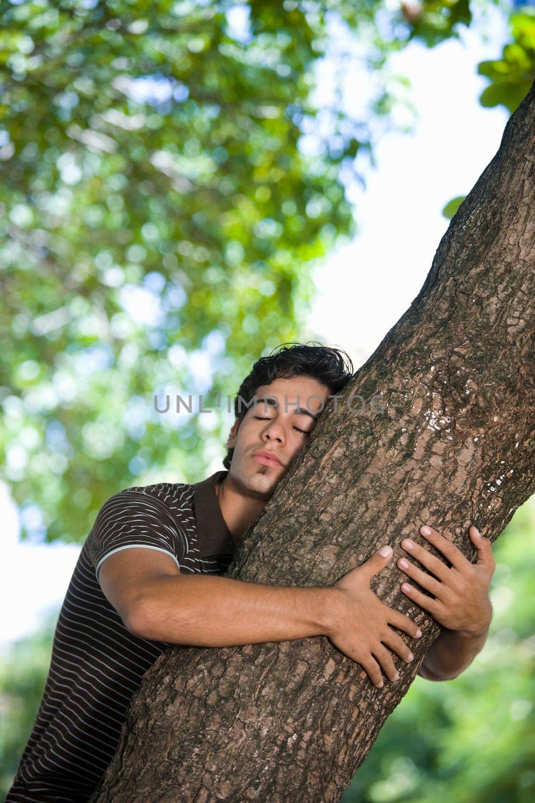 Young man hugging a tree trunk
