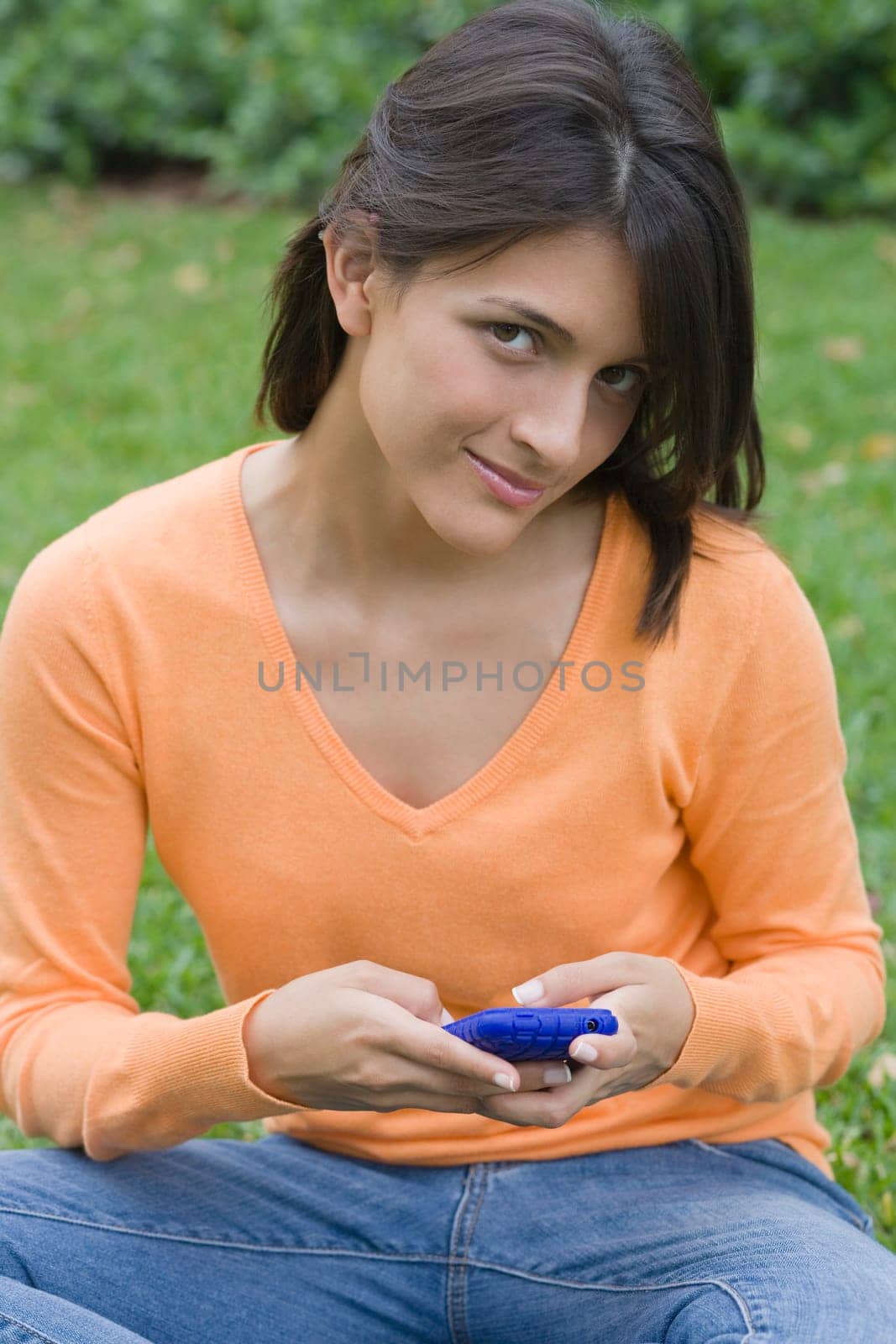 Teenage girl holding a mobile phone in a park