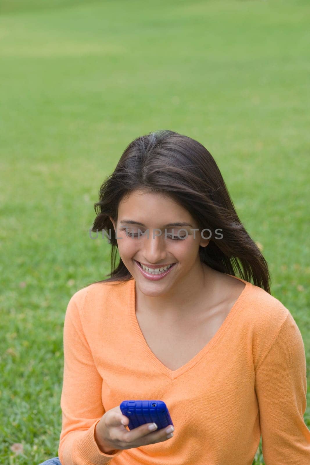 Teenage girl text messaging on a mobile phone in a park