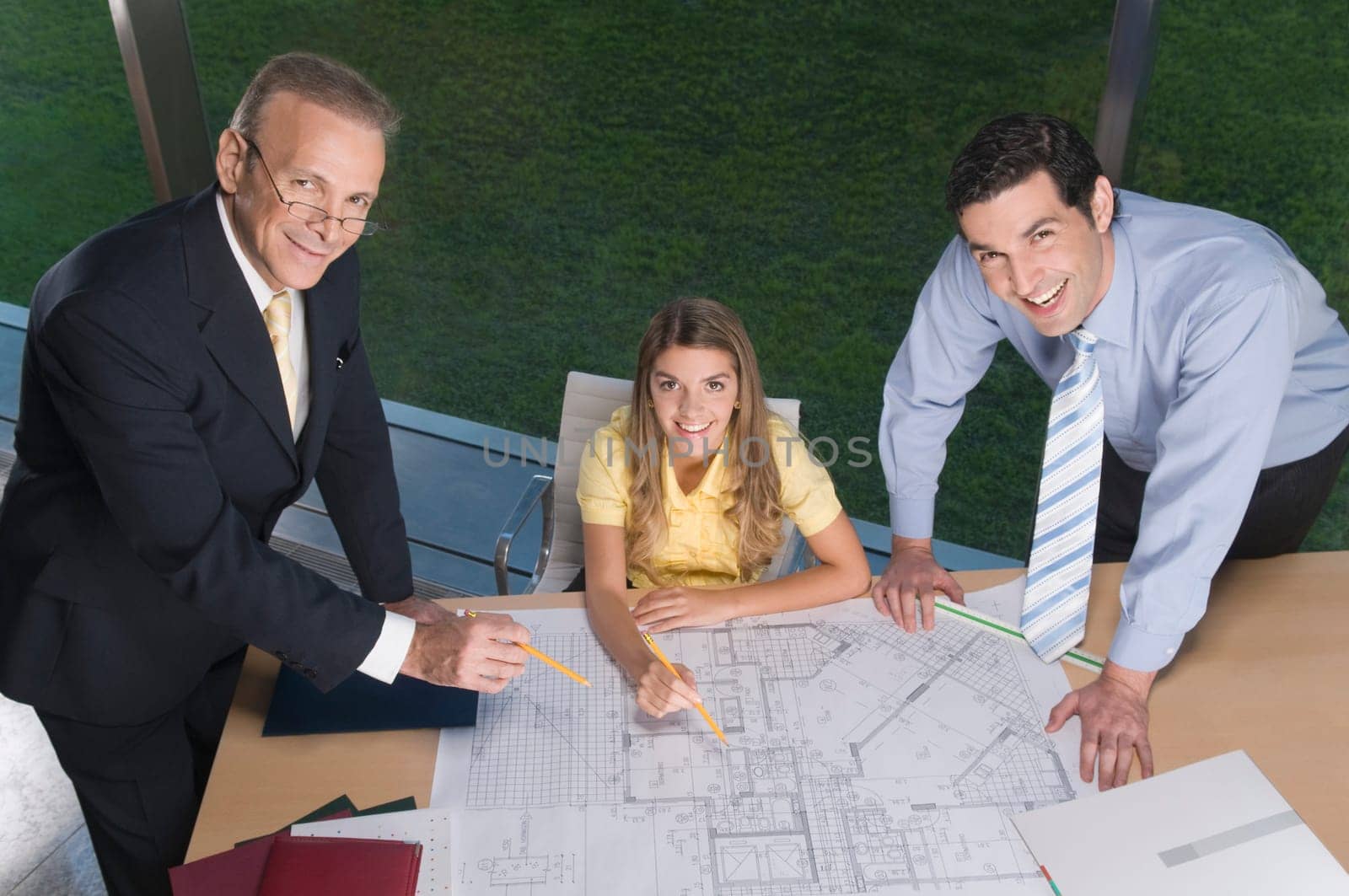 Portrait of business executives discussing a blueprint in an office