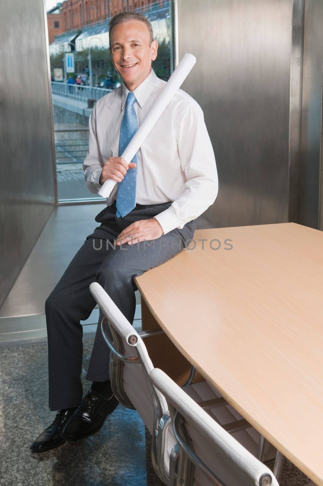 Businessman holding a chart and smiling in a board room