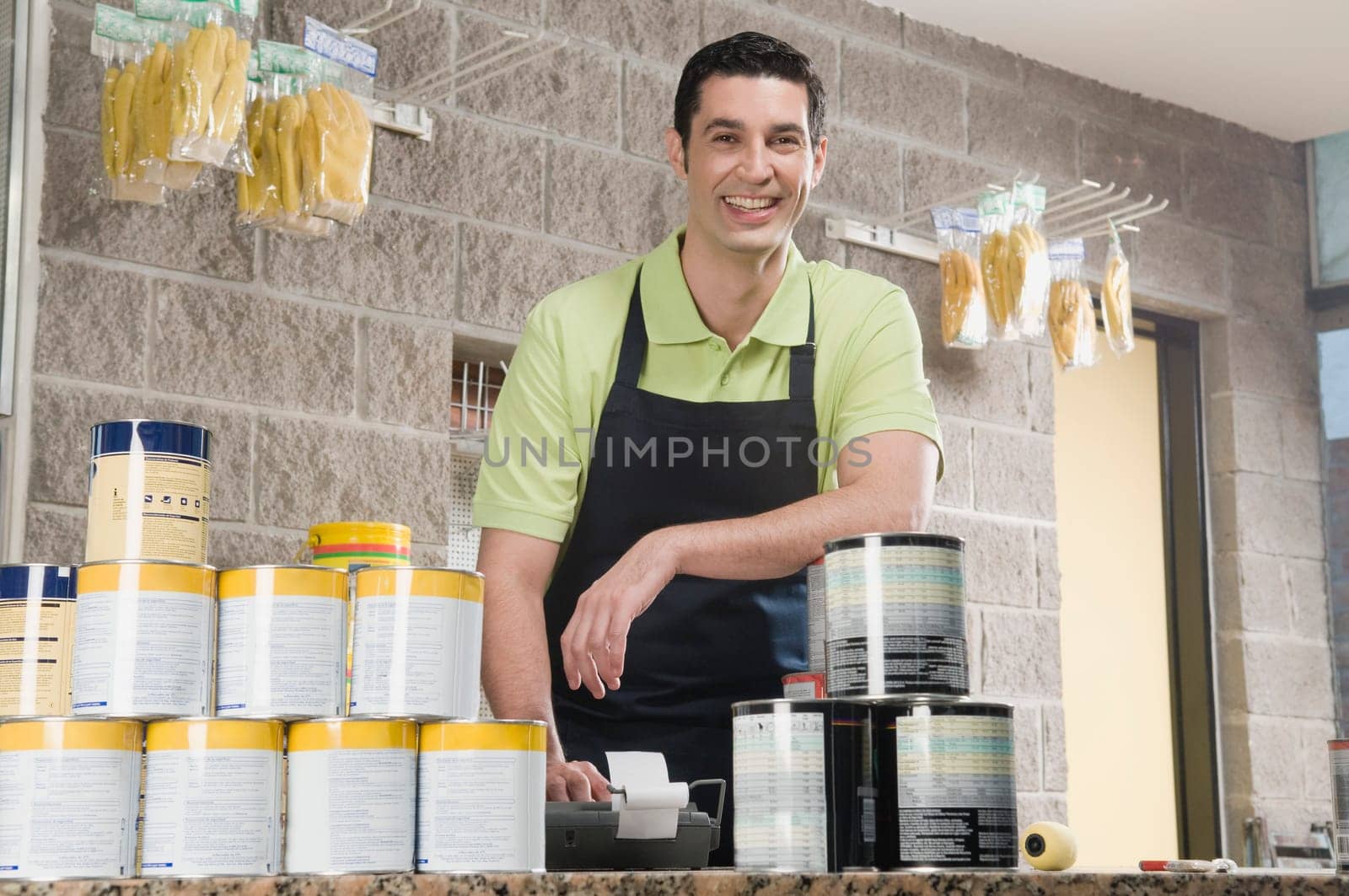 Sales clerk standing at the counter of a paint shop and smiling