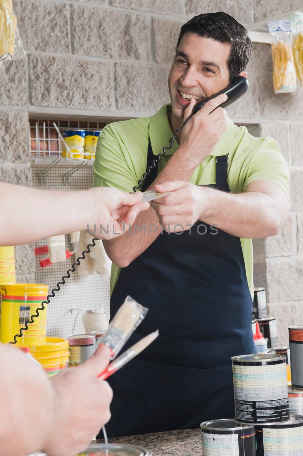 Sales clerk talking on the telephone and giving a credit card to a customer