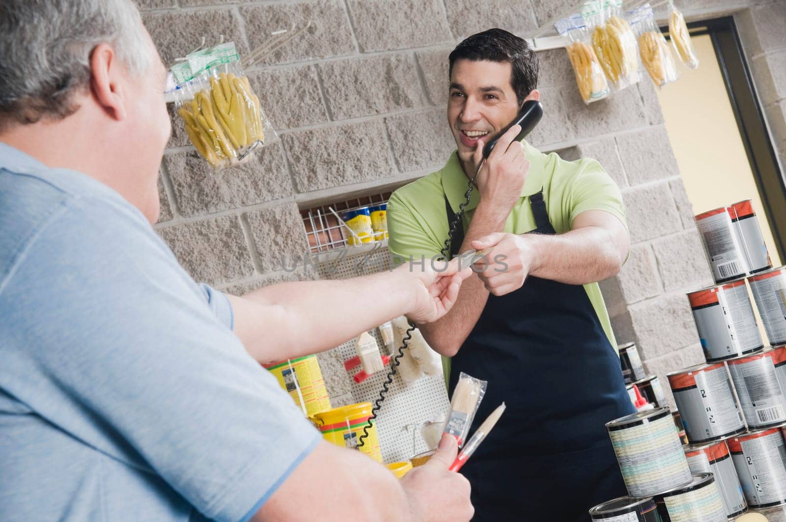 Sales clerk talking on the telephone and giving a credit card to a customer