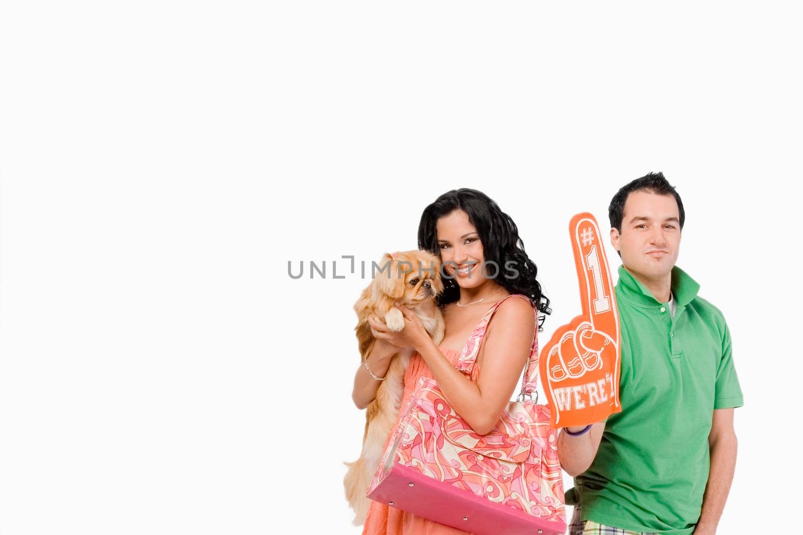 Portrait of a young woman holding a dog and a young man showing a foam finger