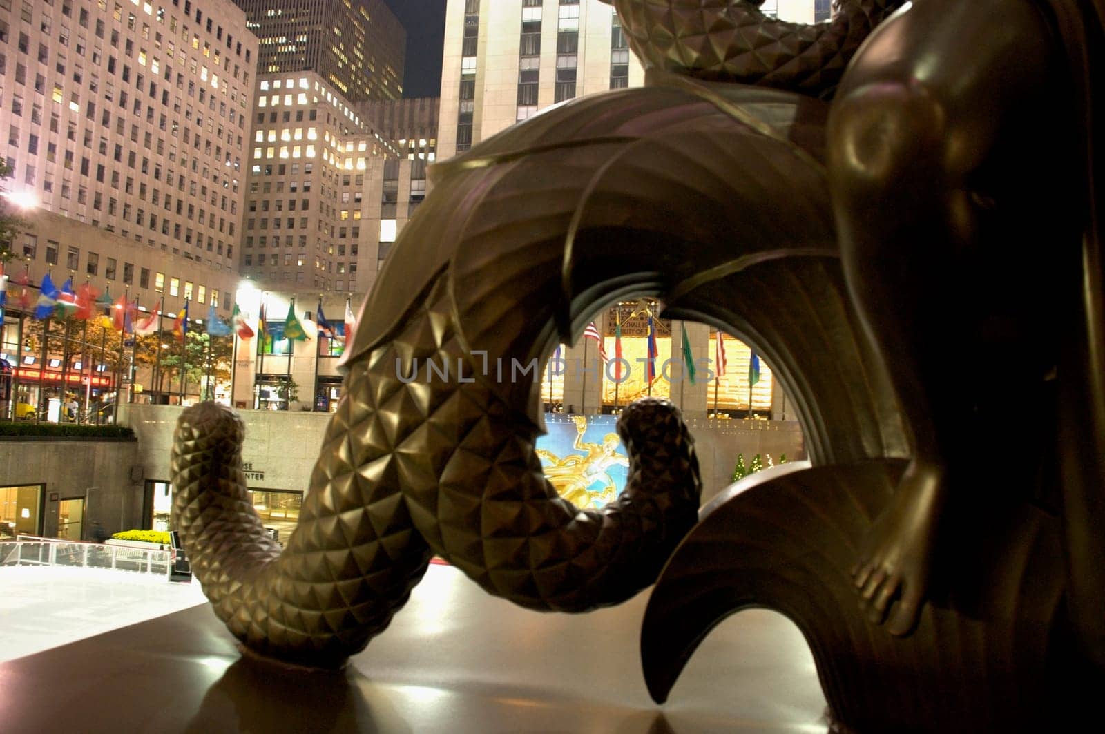 Close-up of a statue with buildings lit up at night in the background