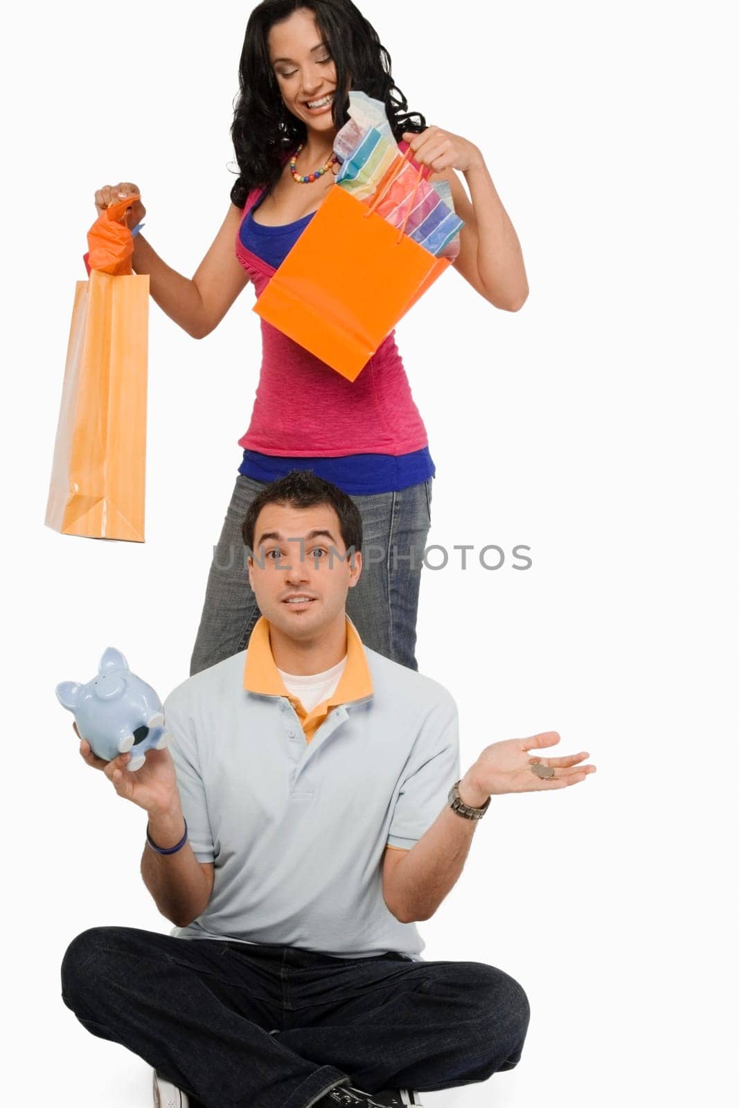 Portrait of a young man sitting and a young woman standing behind him holding shopping bags