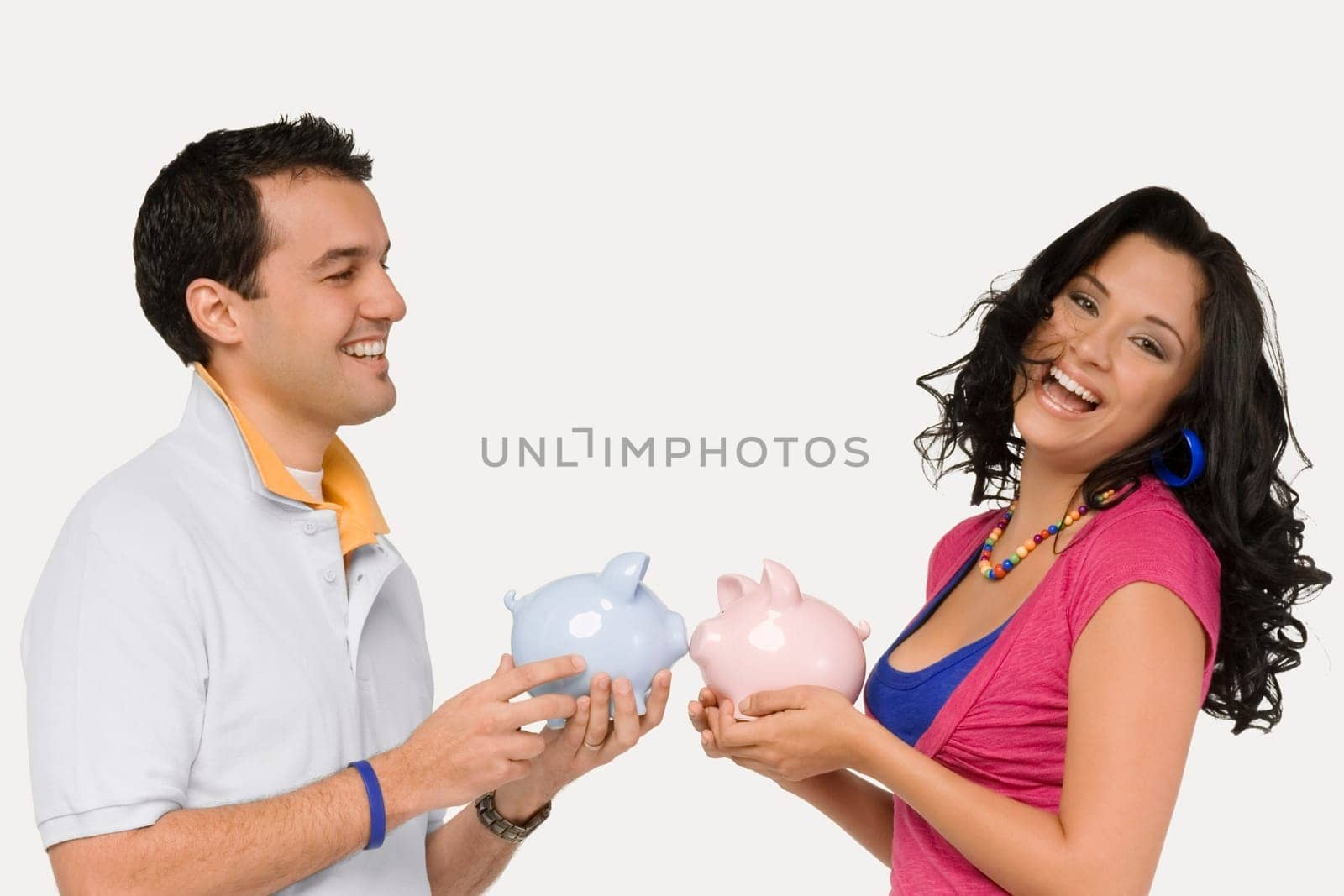 Side profile of a young couple holding piggy banks and smiling